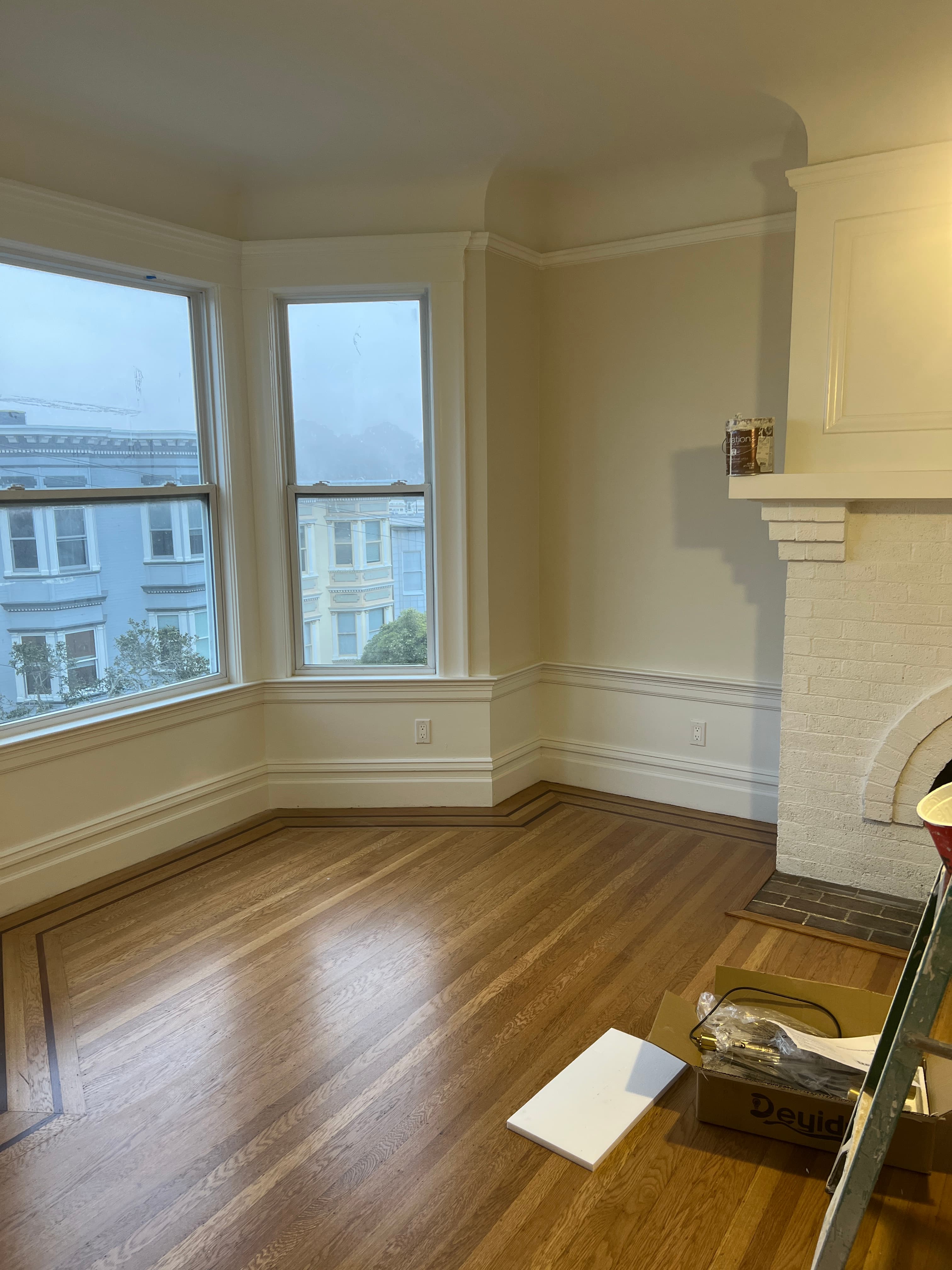White brick fireplace and polished hardwood floors in a room with large city-view windows.