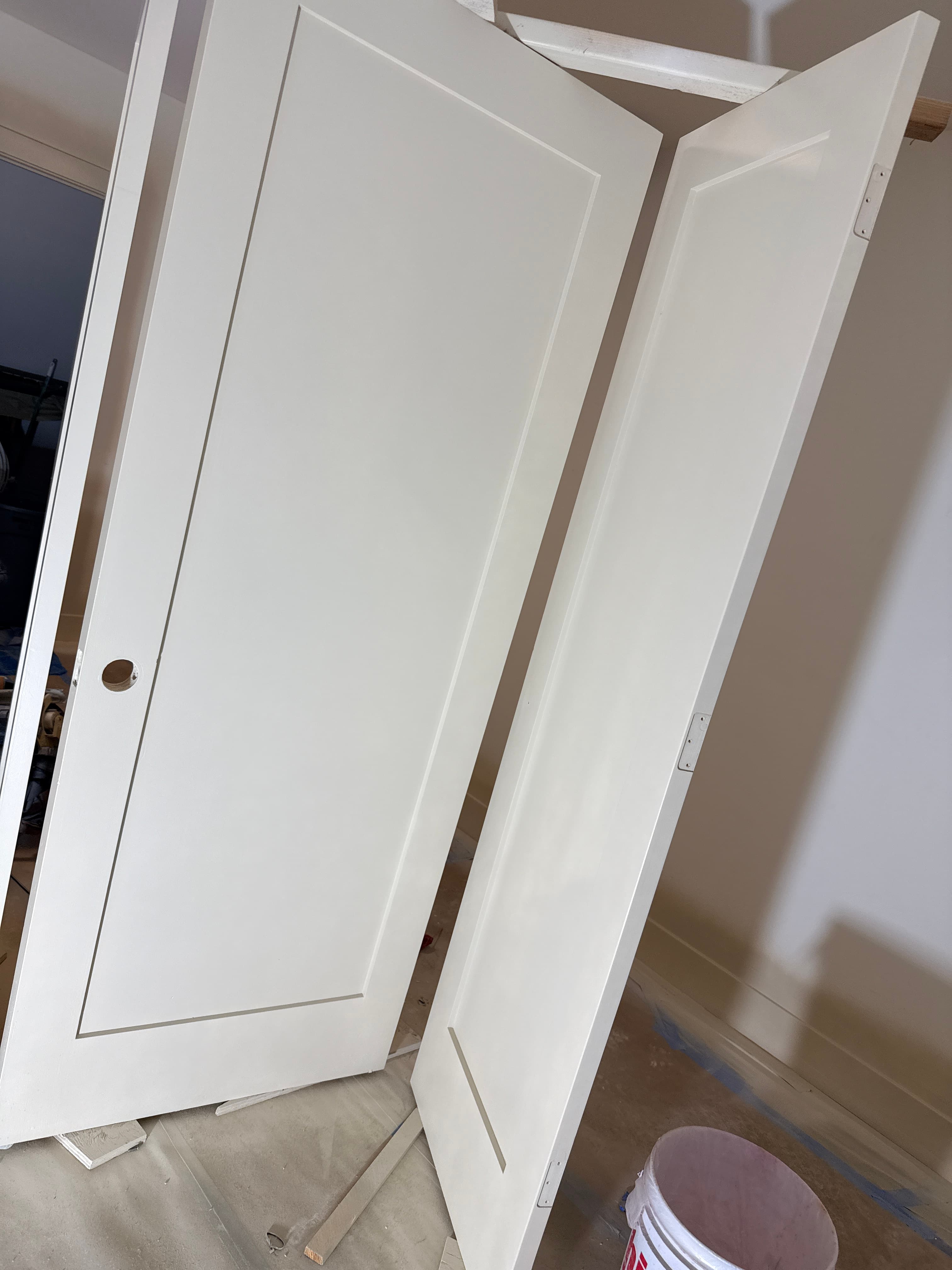 Two white shaker style interior doors leaning against a wall in a room under renovation.