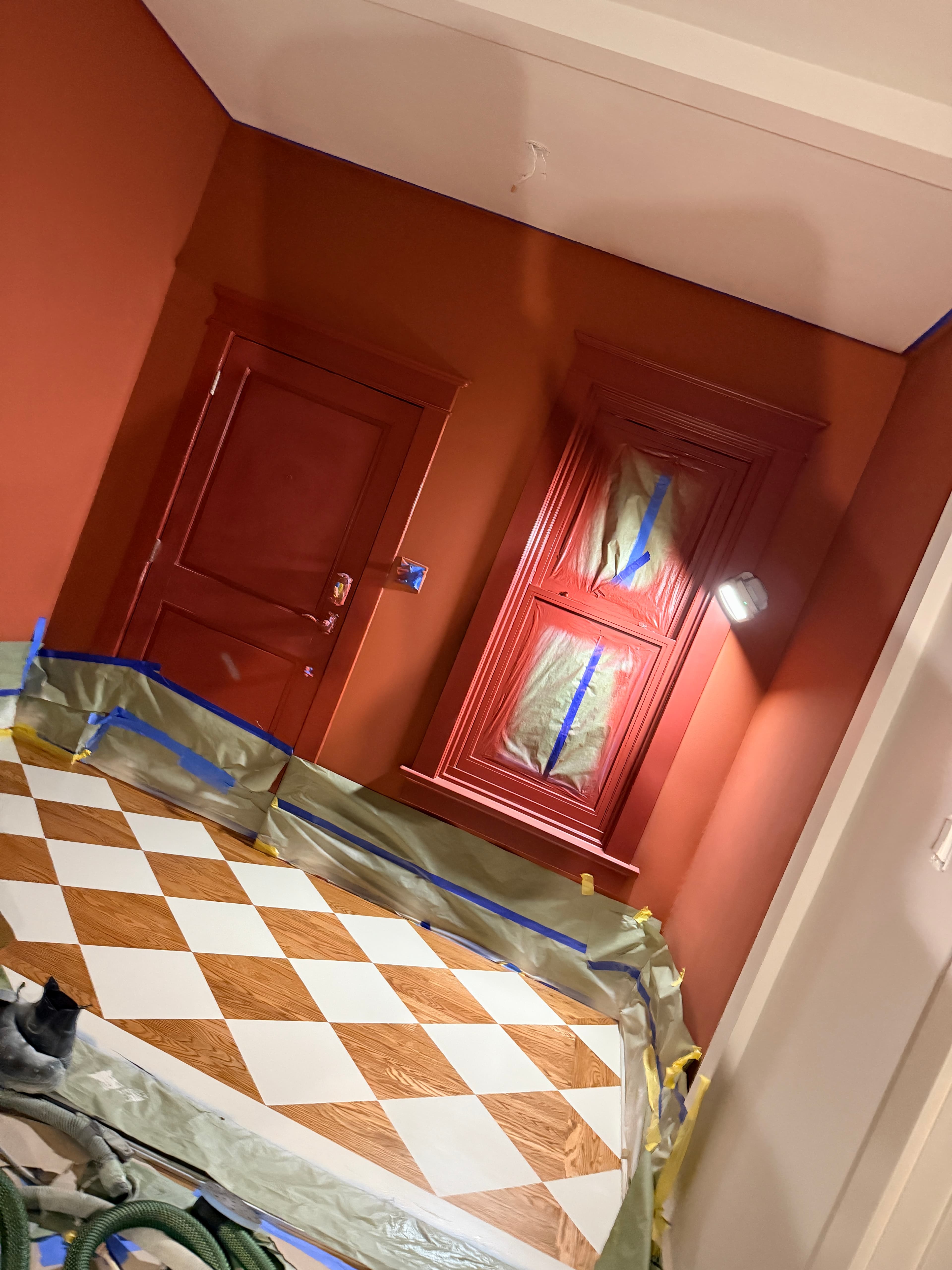 Terracotta walls and cabinets under renovation with a brown and white diamond patterned floor.