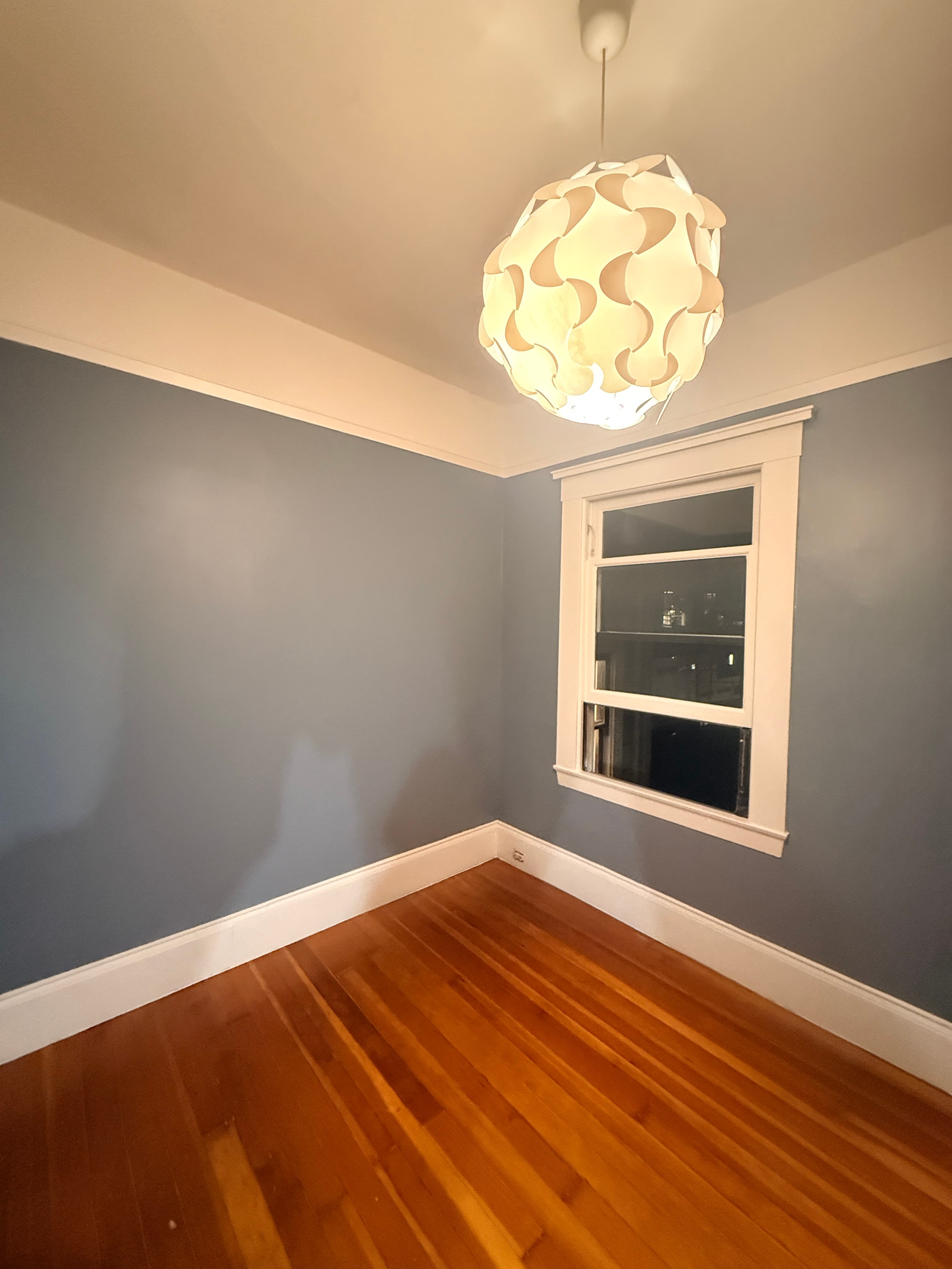 Modern white pendant light in a room with blue walls, white trim, and wooden floors.
